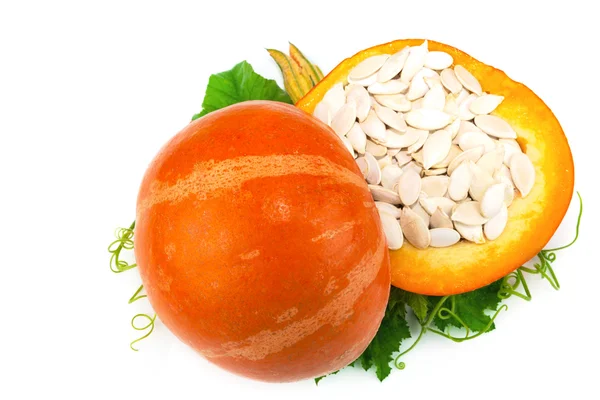 Cut pumpkin with pumpkin seeds and green leaves — Stock Photo, Image