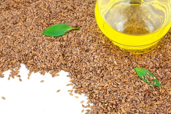 Flax seeds and glass bottle of oil with green leaves — Stock Photo, Image