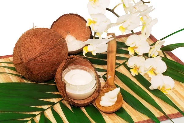 Cocos de coco com creme, colher, orquídea e folhas de palma — Fotografia de Stock