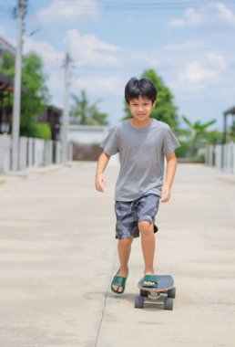 Sokakların ve evlerin arka planında Sörf yapan Asyalı çocuk