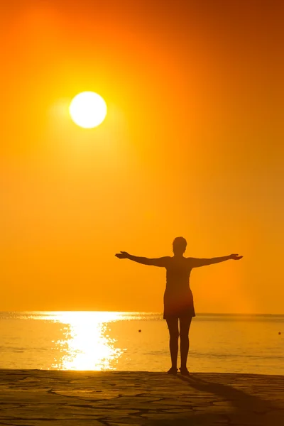 Silhouette einer Frau, die im Sonnenuntergang Yoga praktiziert — Stockfoto