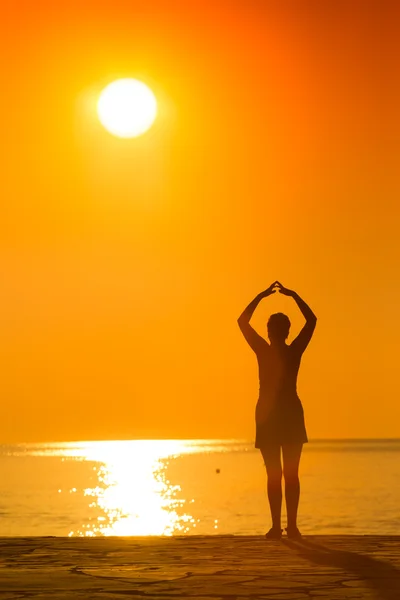 Silhouette einer Frau, die im Sonnenuntergang Yoga praktiziert — Stockfoto