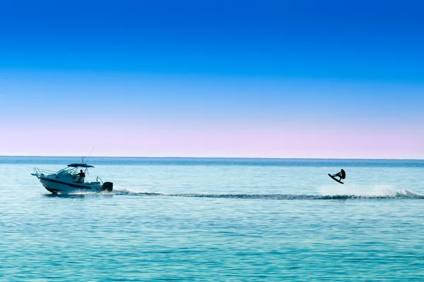 Silhuett av motorbåt och hoppning wakeboarder — Stockfoto