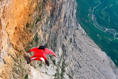 Wingsuit B.A.S.E. jumper jumps off a cliff in Italy clipart