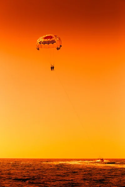 Sílhueta sépia de duas pessoas parasailing sobre o mar — Fotografia de Stock