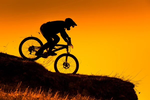 下り坂に山の自転車に乗る夕暮れ時のシルエット — ストック写真