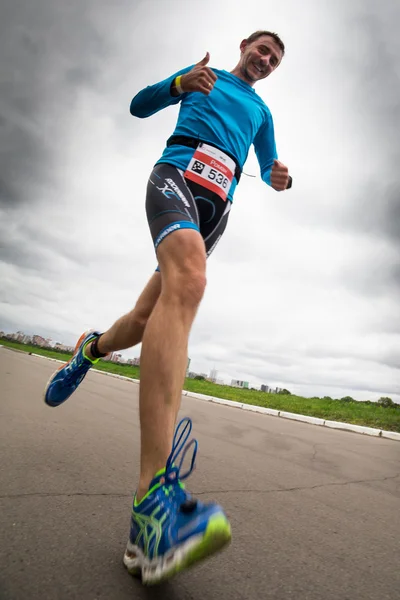 Mosca, Russia, 16 agosto. Pollici-up triatleta corre durante la gara di triathlon, vista dal basso — Foto Stock