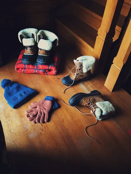 Теплая зимняя одежда на полу: шляпа, перчатки, шарф, сапоги — стоковое фото