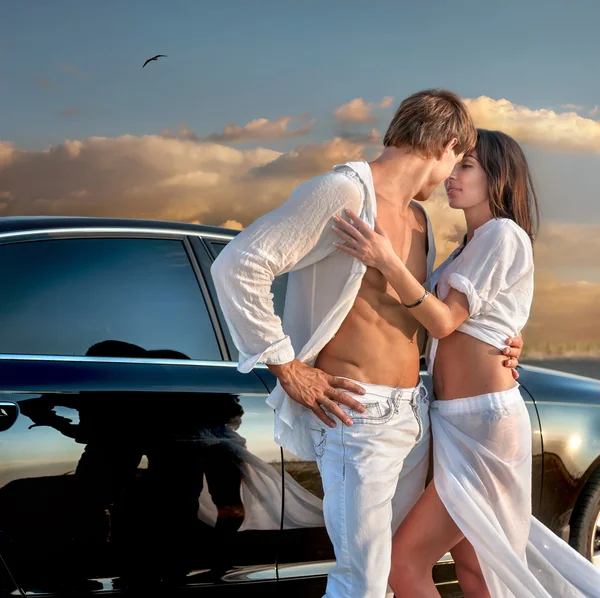 Влюбленная пара рядом с машиной на закате — стоковое фото