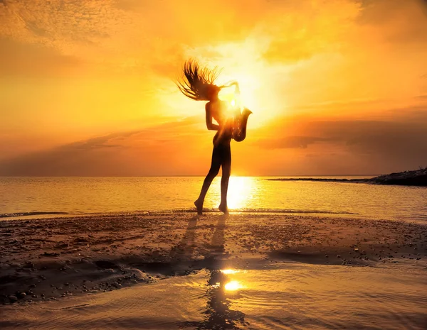 Woman playing saxophone on the beach — Stock Photo, Image