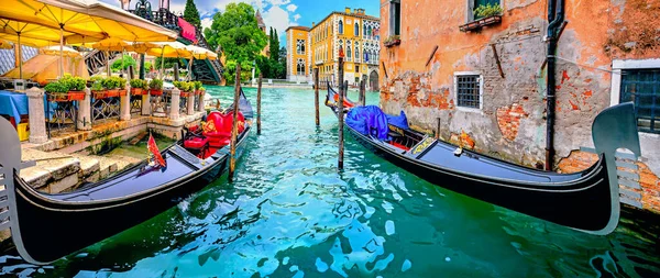 Scenic panoramic landscape with gondolas by wharf of open cafe terrace on Grand Canal in Venice. Italy