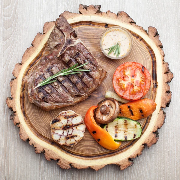 Porción de carne de hueso t barbacoa con salsa y verduras a la parrilla Fotos de stock