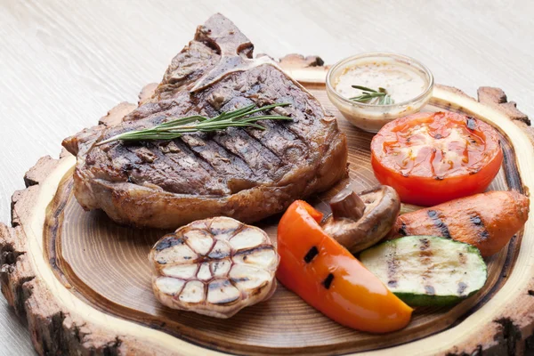 Porción de carne de hueso t barbacoa con salsa y verduras a la parrilla Imágenes de stock libres de derechos