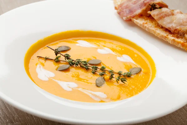 Pumpkin cream soup puree with bread slice, bacon and seeds — Stockfoto