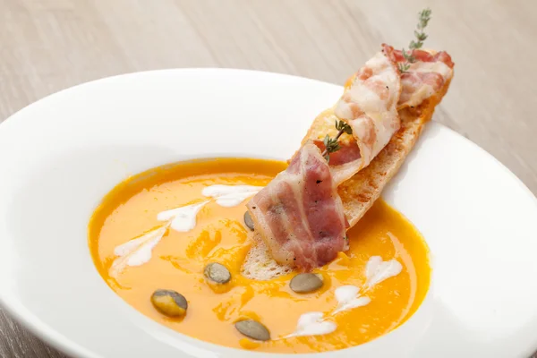 Pumpkin cream soup puree with bread slice, bacon and seeds — Stockfoto