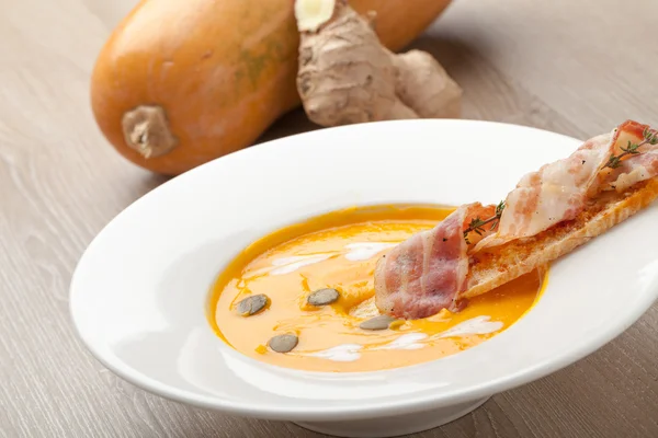 Pumpkin cream soup puree with bread slice, bacon and seeds — Stockfoto