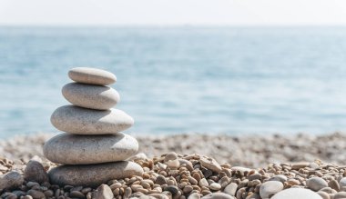 Zen rahatla. Güneşli bir havada kumsalda taş piramidi. Meditasyon, yoga ve masaj için arka plan