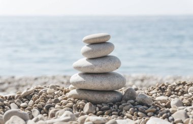 Zen rahatla. Güneşli bir havada kumsalda taş piramidi. Meditasyon, yoga ve masaj için arka plan