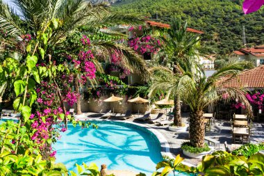 Lüks tropikal tatil köyü ya da turkuaz havuzlu, güneşli yataklı, şemsiyeli ve palmiyeli özel villa. Rahatlama ve tatil kavramı.