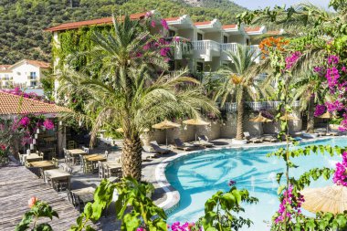 Lüks tropikal tatil köyü ya da turkuaz havuzlu, güneşli yataklı, şemsiyeli ve palmiyeli özel villa. Rahatlama ve tatil kavramı.