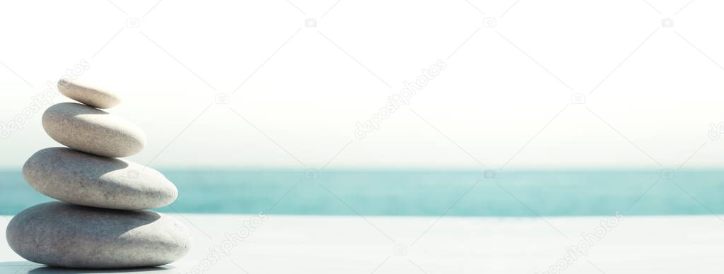 Zen relax banner background. A pyramid of stones on the beach in clear sunny weather. Background for meditation, yoga and massage