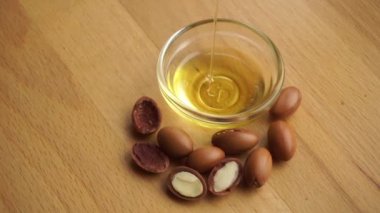 Argan yağı, ahşap zemin üzerinde argan tohumları olan cam bir kâseye konur. Argan yağı bazlı kozmetik konsepti.