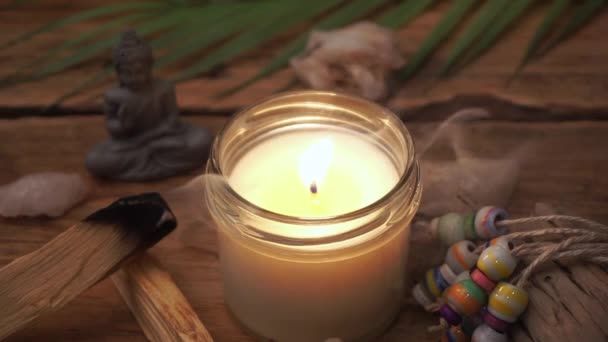 Домашняя свеча с пламенем на деревянном столе с эзотерическими вещами, благовониями и декором. Домашний комфорт, йога, медитация, расслабление и отдых. — стоковое видео