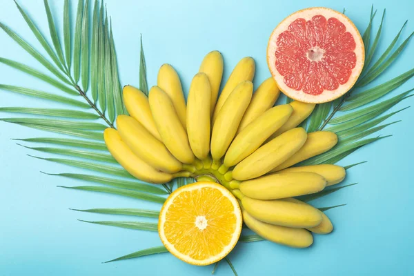 Tropical fruits summer background. Bananas, oranges and grapefruits on a colored blue background.  Composition of tropical fruits