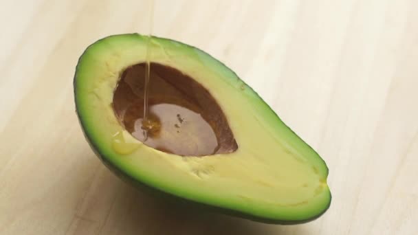 Abacate e óleo de abacate derramando sobre a fruta. Óleo de abacate para alimentos e cosméticos. — Vídeo de Stock