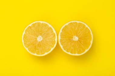 Lemon slices on a yellow minimal background. Bright juicy lemon on a yellow blank isolated background. Summer, sun, health concept.