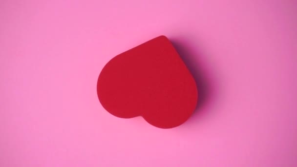 ピンクの背景の赤いハート。バレンタインデー、愛、ロマンス、結婚式のコンセプト。心を持つ最小限の芸術創造的なビデオ — ストック動画