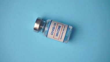 Coronavirus covid aşıları bir tıp laboratuarında mavi arka planda döner. Aşı, koronavirüs salgınından korunma.