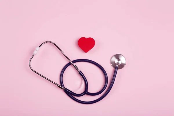 World heart day background. Heart as a symbol of health, treatment, charity, donation and cardiology on a pink background with a medical statoscope.