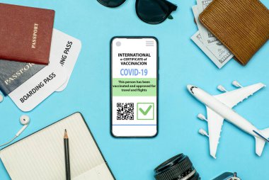 Coronavirus aşı sertifikası ya da gezginler için aşı pasaportu. COVID-19 uluslararası seyahat için akıllı cep telefonu uygulamasındaki e-pasaport. Oyuncak uçakla mavi arkaplan 