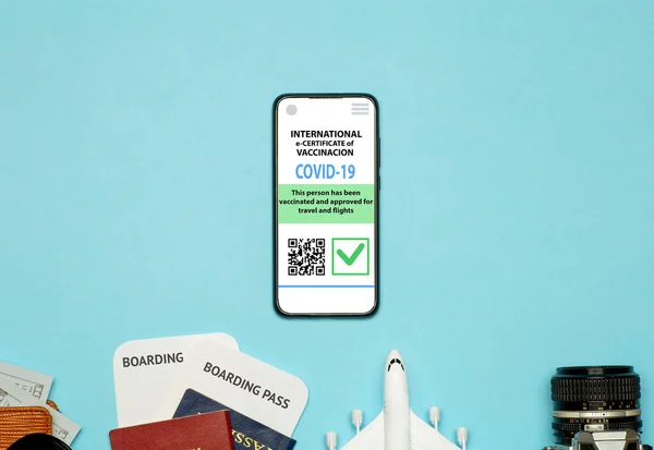 Coronavirus vaccination certificate or vaccine passport for travellers concept. COVID-19 immunity e-passport in the smartphone mobile app for international travelling. Blue background with toy plane