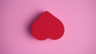 Pembe arka plandaki kırmızı kalp. Sevgililer günü, aşk, romantizm, düğün konsepti. Asgari sanat ve kalbi olan yaratıcı video