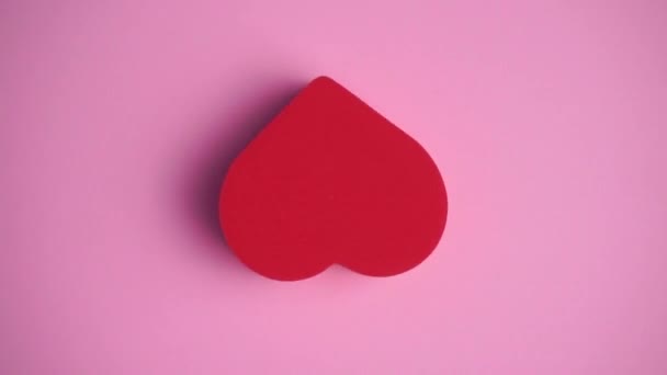 ピンクの背景の赤いハート。バレンタインデー、愛、ロマンス、結婚式のコンセプト。心を持つ最小限の芸術創造的なビデオ — ストック動画