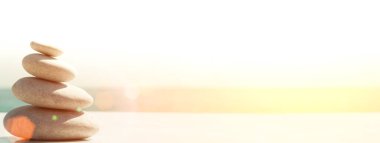 Zen gevşeme afiş arka planı. Güneşli bir havada kumsalda taş piramidi. Meditasyon, yoga ve masaj için arka plan