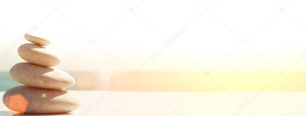 Zen relax banner background. A pyramid of stones on the beach in clear sunny weather. Background for meditation, yoga and massage