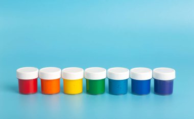 Açık mavi arka planda gökkuşağı renklerinde akrilik boya. Resim için boya, gökkuşağı renk kavramı.