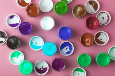 Çizim için çeşitli renklerdeki akrilik boyalar masanın üzerinde açık. Boya kutularından parlak renkli arkaplan