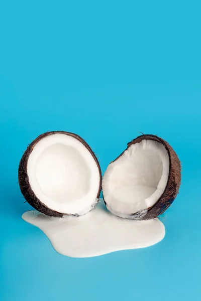 Coconut cream or butter with fresh coconuts on a blue background. White cream juice dripping from coconut.