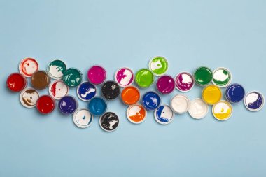 Çizim için çeşitli renklerdeki akrilik boyalar masanın üzerinde açık. Boya kutularından parlak renkli arkaplan