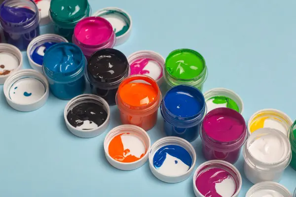 Acrylic paints of various colors for drawing are open on the table. Bright colorful background from paint cans