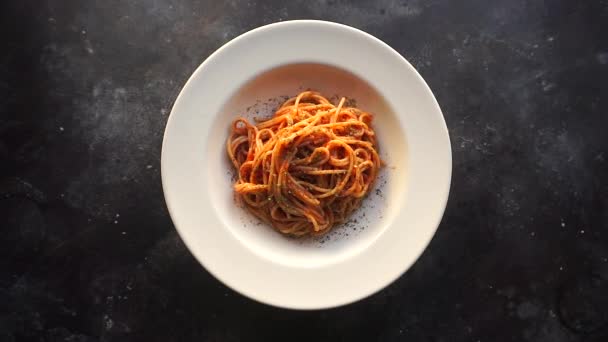 Pasta met tomatensaus. Italiaanse spaghetti pasta met tomatensaus draait op een witte plaat tegen een keukenachtergrond. Italiaanse keuken. — Stockvideo