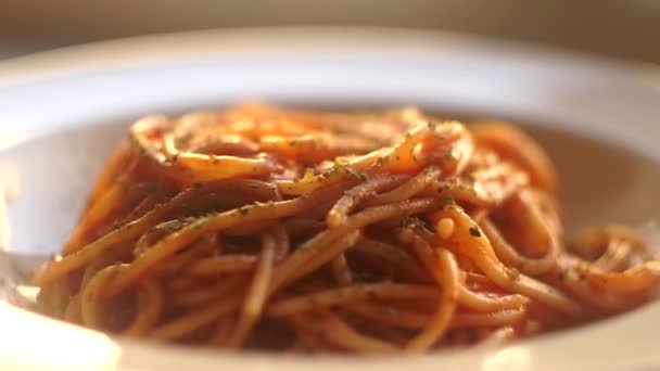 Ζυμαρικά με σάλτσα ντομάτας. Τα ιταλικά μακαρόνια με σάλτσα ντομάτας περιστρέφονται σε λευκό πιάτο πάνω σε φόντο κουζίνας. Ιταλική κουζίνα. — Αρχείο Βίντεο