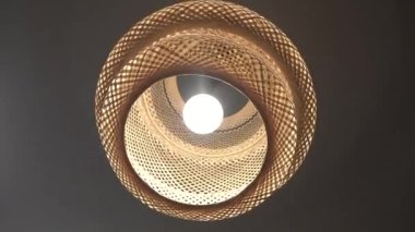 Odada dönen ampullü bir bambu ahşap abajur. Yapay aydınlatma efekti, iç ve bambu lamba tasarımı kavramı.