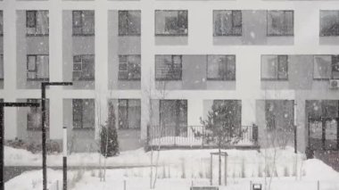 Kışın evlerin arka planında kar yağışı var. Kentsel bir bölgenin yerleşim bölgesinde kar ve tipiweather forecast