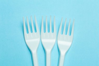 Mavi arka planda plastik çatallar. Plastik atık ve kirlilik kavramı