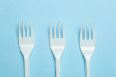 Mavi arka planda plastik çatallar. Plastik atık ve kirlilik kavramı